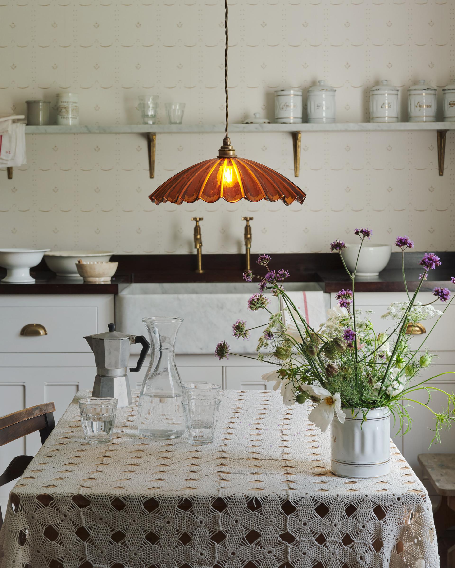 A large amber frilly glass light hanging in a white kitchen.